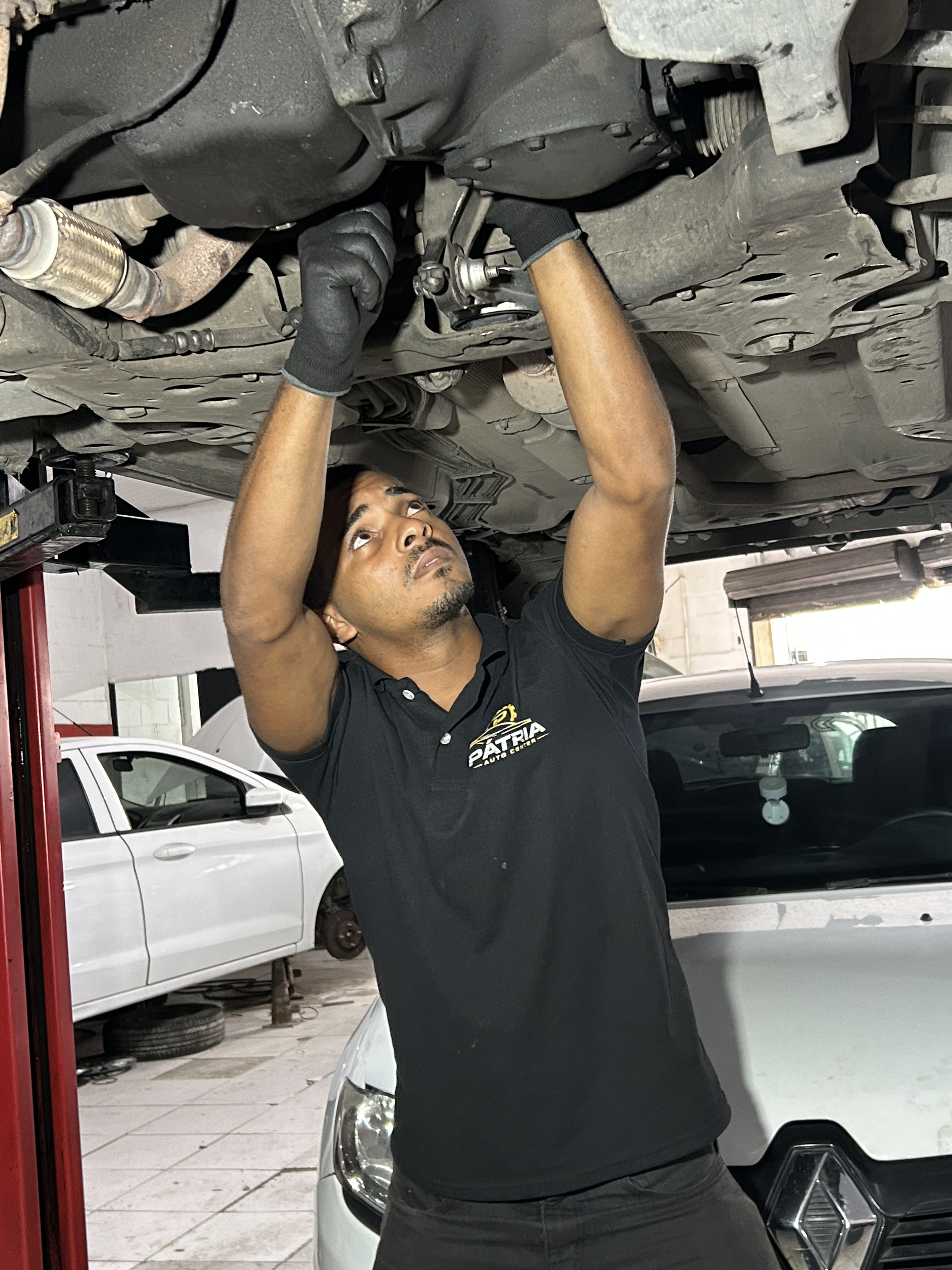 Mecânico trabalhando na parte inferior de um veículo elevado